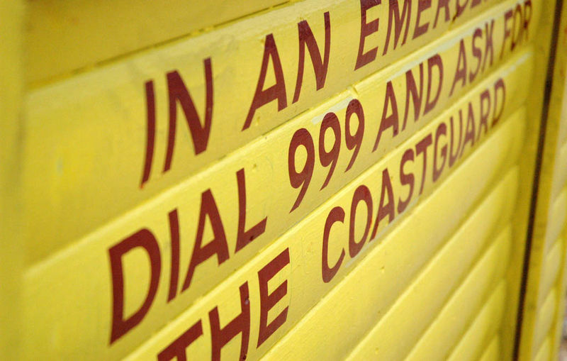 Cartel con el número de emergencias en una playa británica. Foto: Wikipedia